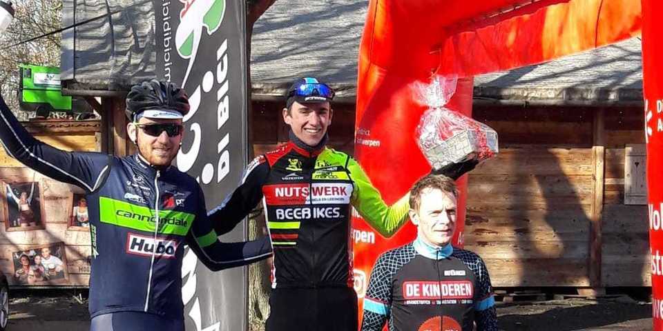 Michiel van Echelpoel wint de eerste Noordkasteelcross: hij staat op het podium met de nummers 2 en 3 en een prijsmand in de hand.